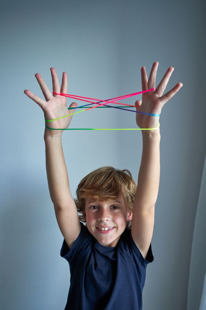 Happy boy playing cats cradle game