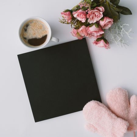 Coffee, mittens and dark paper card with flowers
