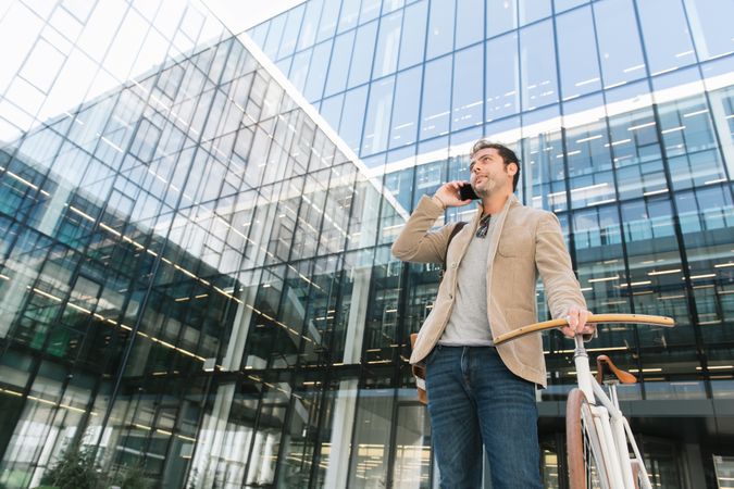 Man phoning while standing against modern building in downtown