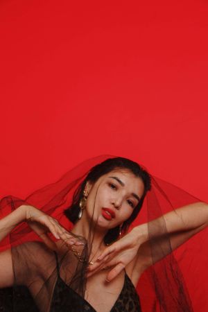 Woman wearing dark veil against red background