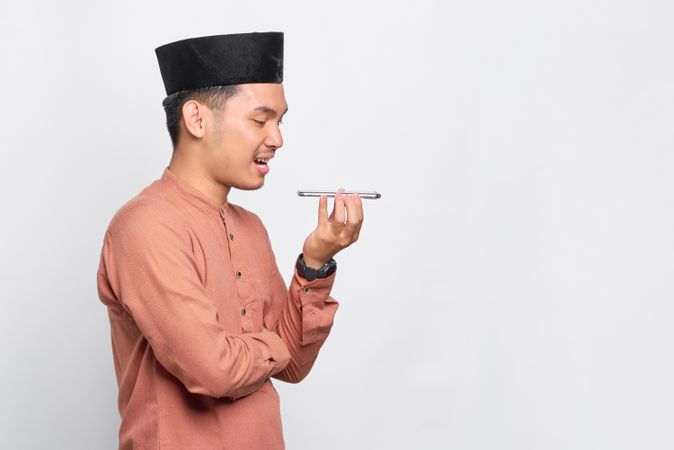 Muslim man in kufi hat talking on speaker phone