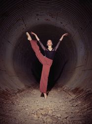 Graceful woman dancing in darkness of underground tunnel