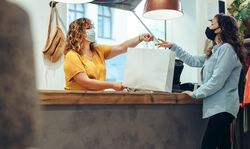Store owner and customer wearing face mask in boutique store