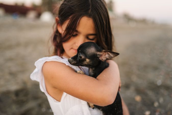 Girl with little dog on sandy beach