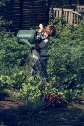 Adorable preteen boy pouring garden beds from watering can