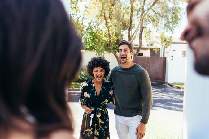 Excited and laughing guests couple coming for housewarming party