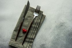 Heart decoration on grey napkin and cutlery