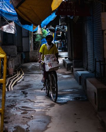 South Asian man riding a bicycle in a narrow alley