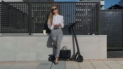 Businesswoman with mobile and her scooter next