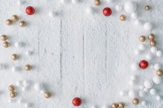 Wooden table background with snow and festive red and gold baubles