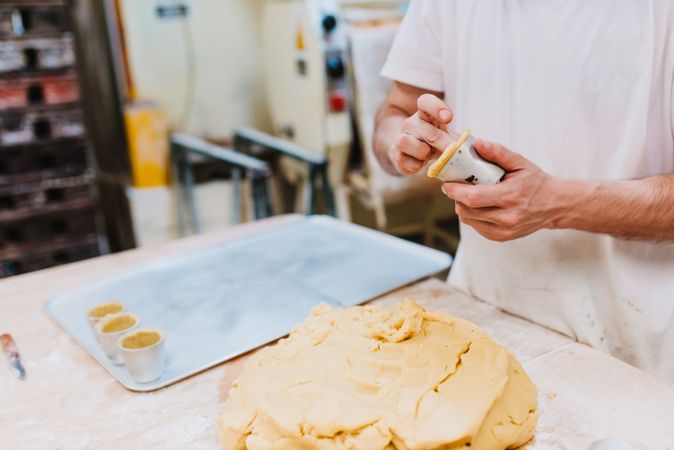 Bearded confectioner putting dough into cup