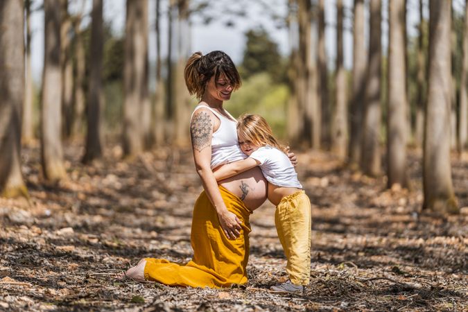 Pregnant mother and little daughter having fun in park