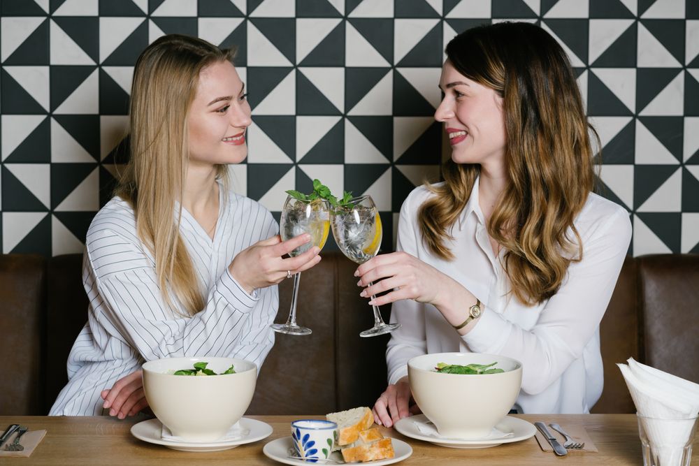 Cheerful friends clinking glasses in cafe