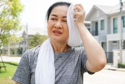 Woman using towel to wipe the sweat after workout