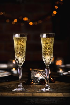 Two crystal flutes full of champagne on wooden table