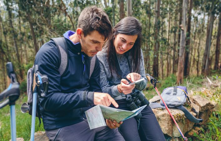 Couple doing trekking sitting looking mobile and map