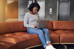 Woman working on laptop on sofa near elevators