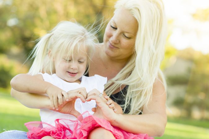 Little Girl With Mother Making Heart Shape with Hands