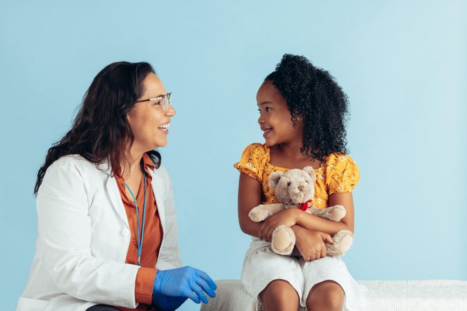Doctor and girl smiling on blue background