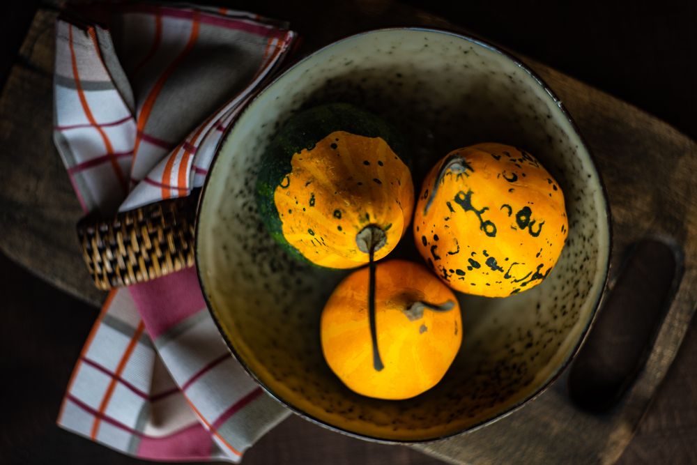 Top view of rustic bowl with three squashes and kitchen towel
