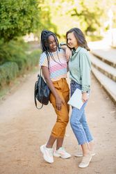 Female friends laughing together in casual clothing in park walk way