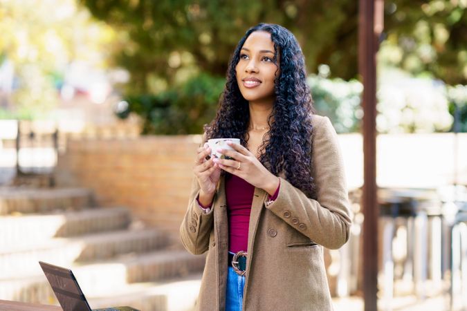 A Confident Woman Happily Enjoys A Cup Of Coffee While Outdoors In A Relaxing Setting