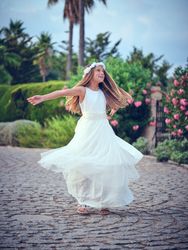 Cheerful child spinning around on pavement in park