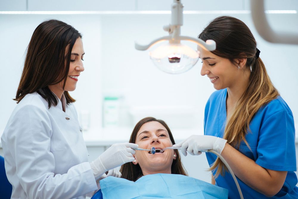 Dentist and assistant examining mouth of patient in chair with t