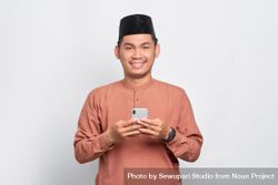 Muslim man in kufi hat smiling with smartphone beRJl0