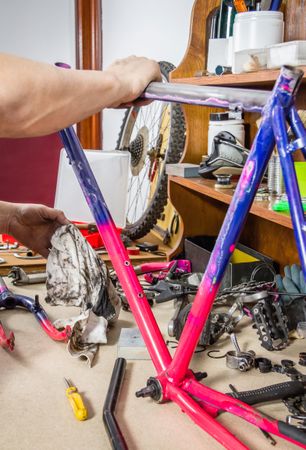 Hands of real bicycle mechanic cleaning frame bike
