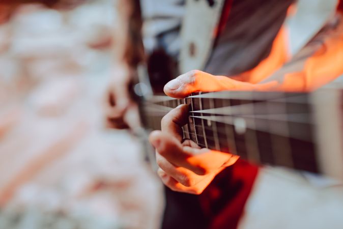 Man clamping strings on guitar neck