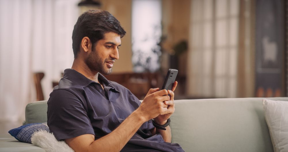 Indian Man Using Smartphone at Home: Engaging in Social Media, Discovering New Music