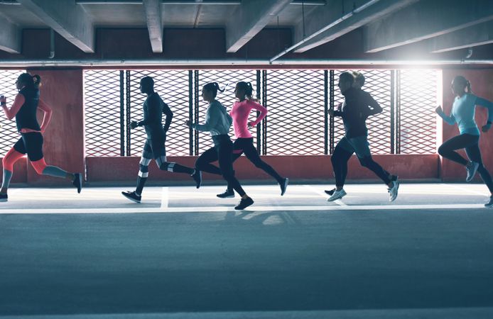 Side view of group of people running in industrial space