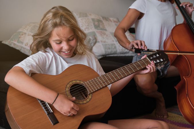 Happy girl playing guitar at home
