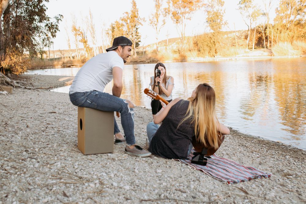 Young woman shooting friend playing guitar