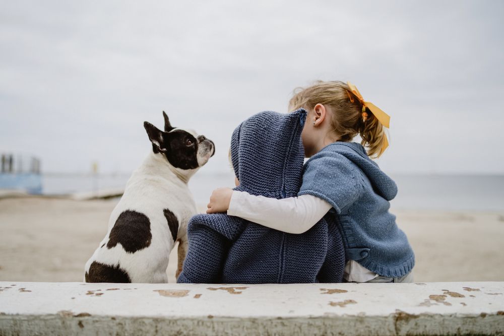 Kids hugging dog on beach