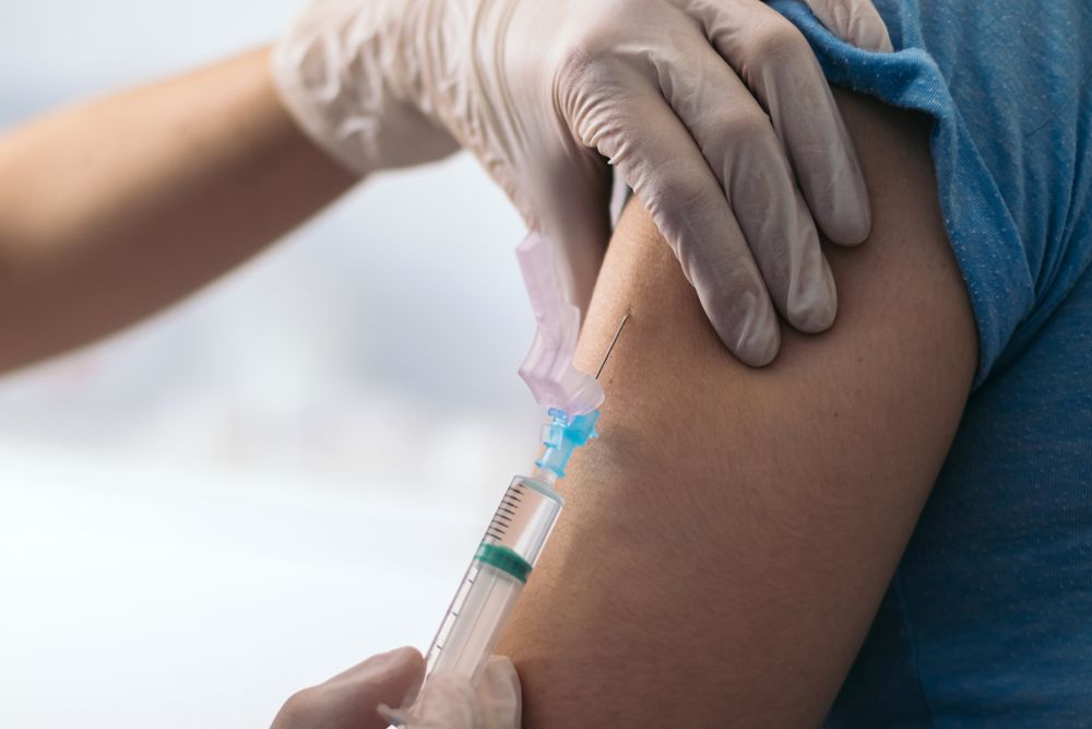 Vaccine in injection needle. Doctor working with patient's arm.