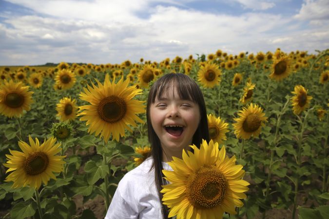 Happy child standing beside giant sunflower