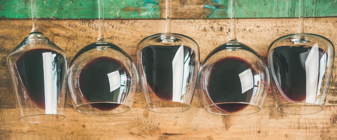 Glasses of red wine glasses laying on wooden background, wide composition