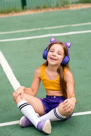 Female child sitting on sports ground