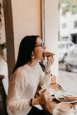 Young woman eating sandwiches in cafe