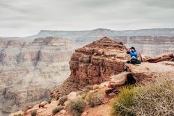 Male having rest on edge of rock and relishing beverage
