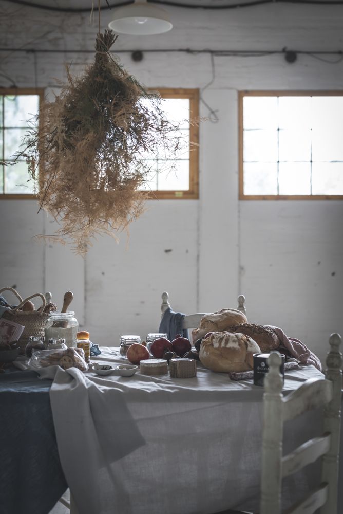 Fresh bread on served table and bunch of dry plant hanging on thread