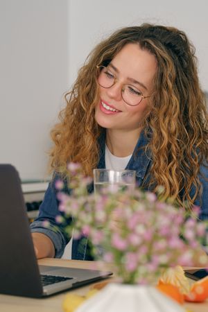 Smiling self employed woman browsing laptop in kitchen