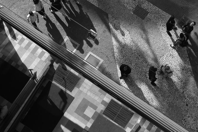 High angle view of people walking on pedestrian lane in grayscale