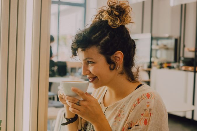 Positive woman drinking coffee in cafe