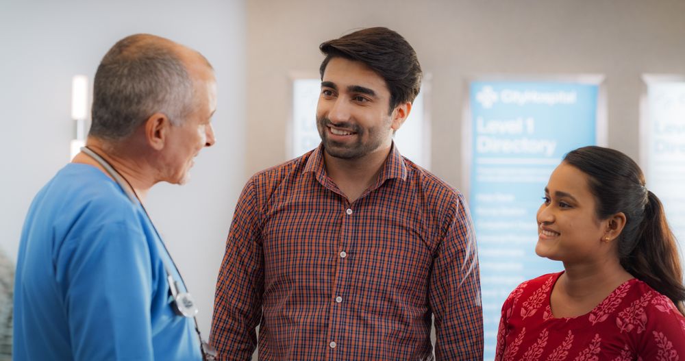 Indian Couple Visiting a Local City Hospital for a Health Check Up: Young Husband and Wife Talking to Their Doctor
