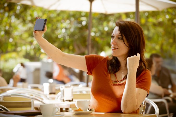 Woman talking selfie with smartphone in cafe