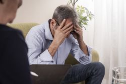 Man in despair with his head in his hands during a therapy session.