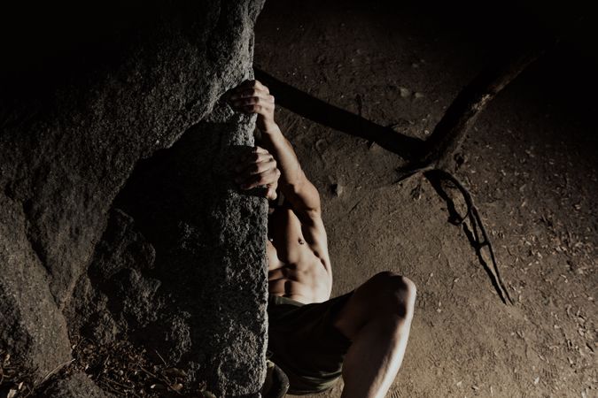 Man practicing rock climbing among large rocks in a forest